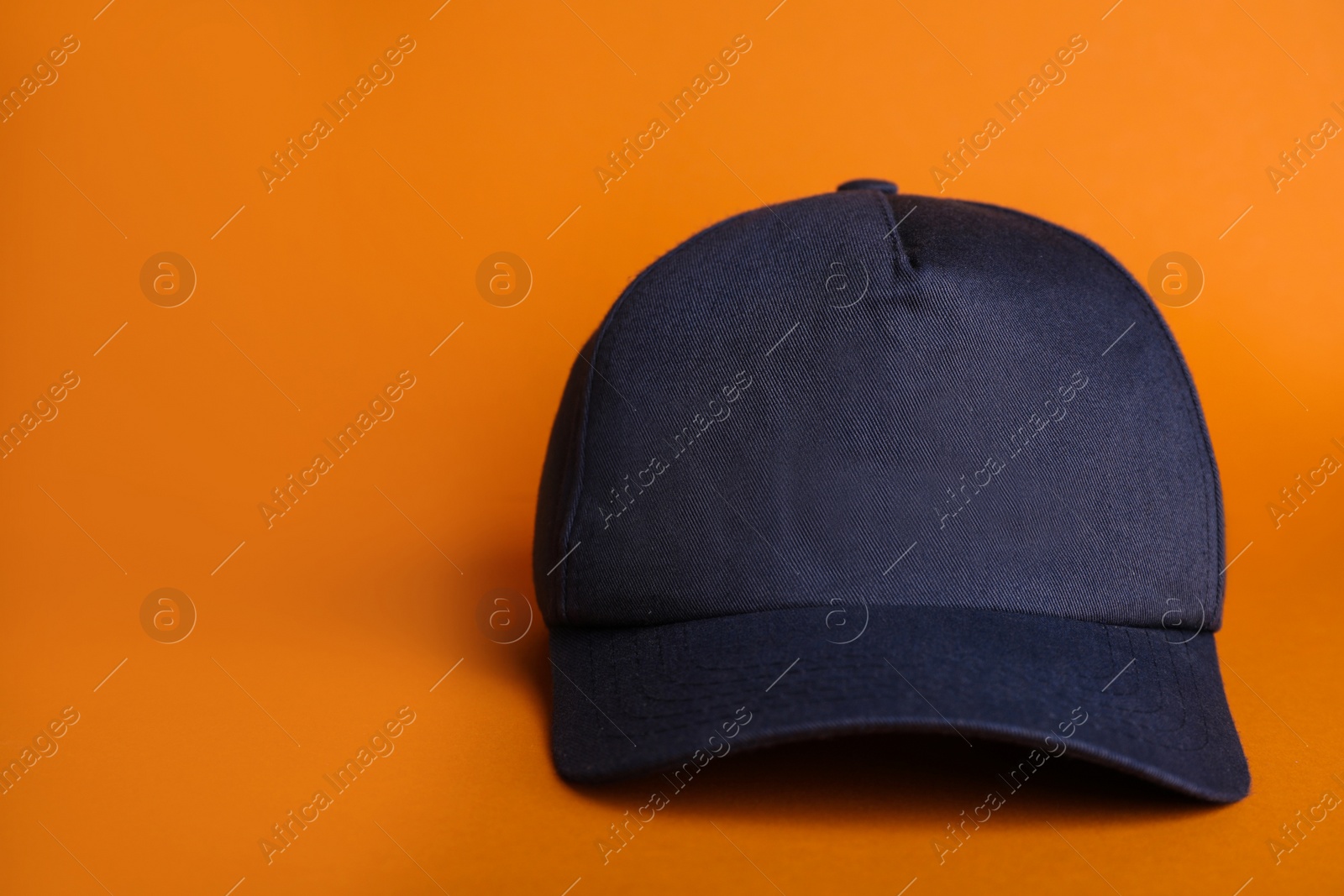 Photo of Baseball cap on orange background, space for text
