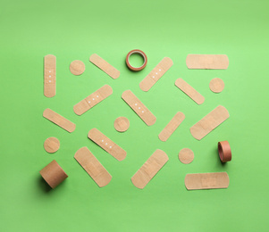 Photo of Different types of sticking plasters on green background, flat lay