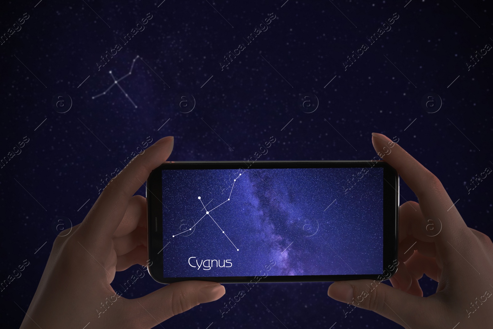 Image of Woman using stargazing app on her phone at night, closeup. Identified stick figure pattern of Swan (Cygnus) constellation on device screen