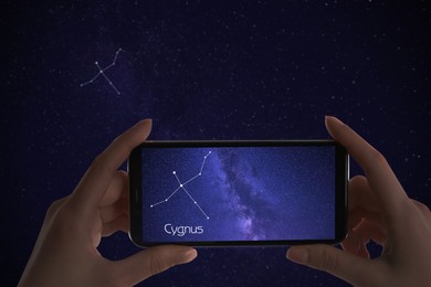 Image of Woman using stargazing app on her phone at night, closeup. Identified stick figure pattern of Swan (Cygnus) constellation on device screen