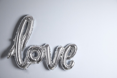 Silver balloon in shape of word LOVE near light wall