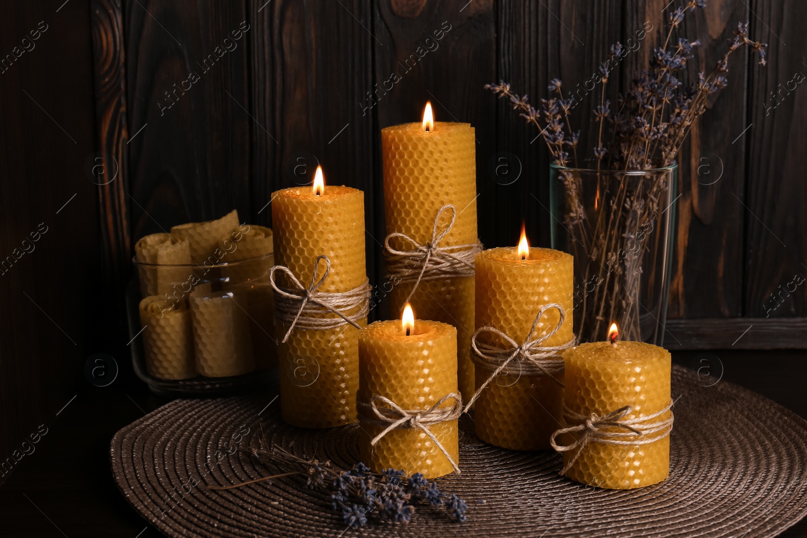 Photo of Beautiful burning beeswax candles and dried lavender flowers on table