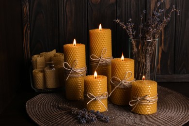 Photo of Beautiful burning beeswax candles and dried lavender flowers on table