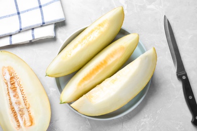Pieces of delicious honeydew melon on light grey marble table, flat lay