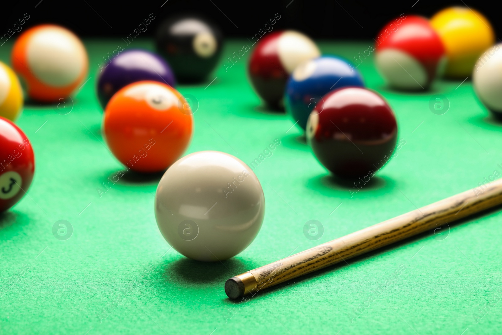 Photo of Many colorful billiard balls and cue on green table