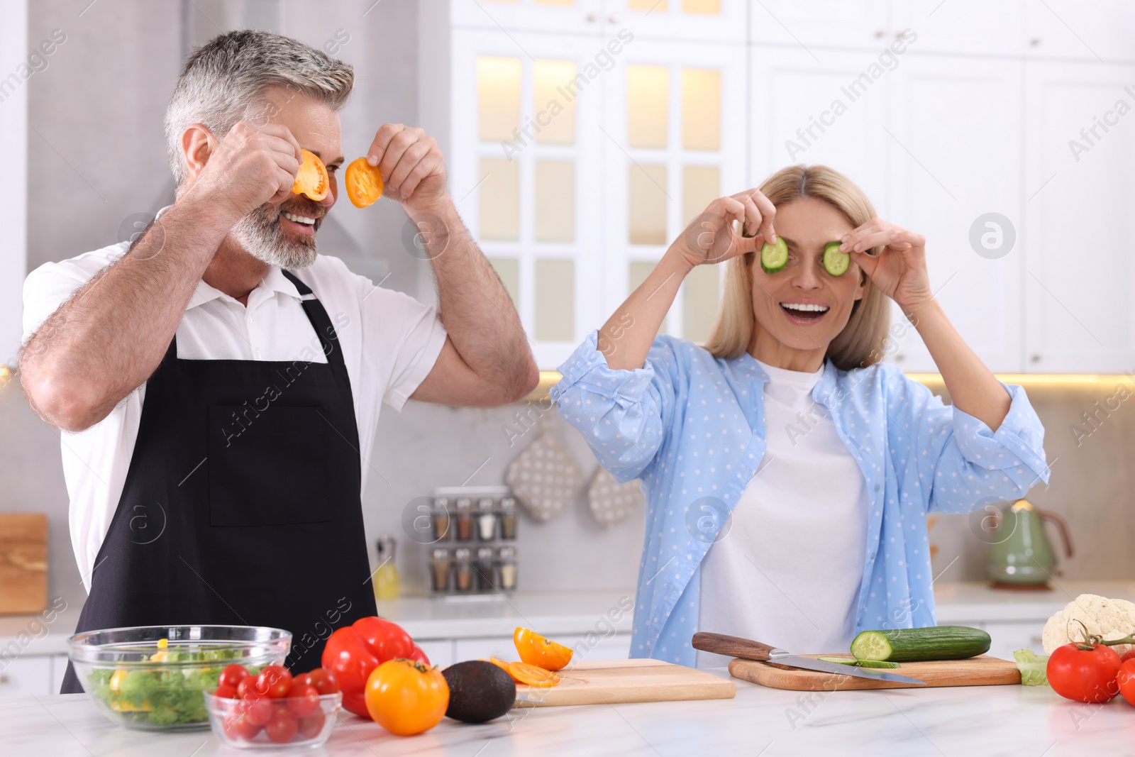 Photo of Happy affectionate couple having fun while cooking together in kitchen