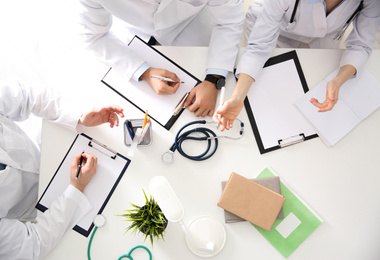 Doctors having meeting at table in office, top view