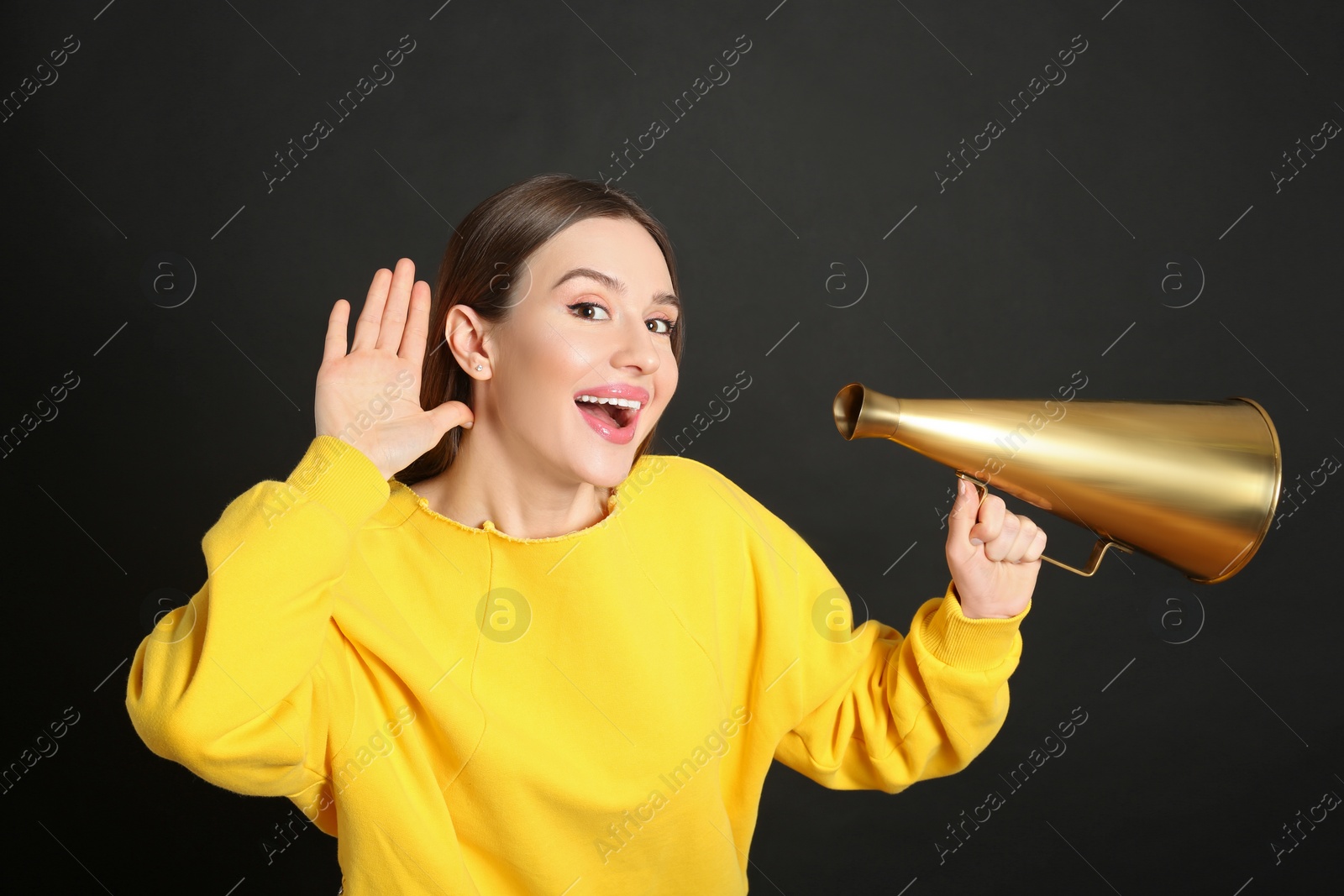 Photo of Young woman with megaphone on black background