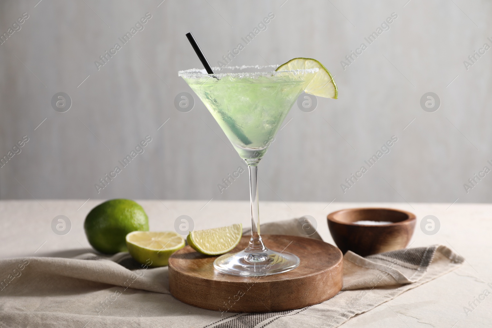 Photo of Delicious Margarita cocktail in glass, salt and limes on table