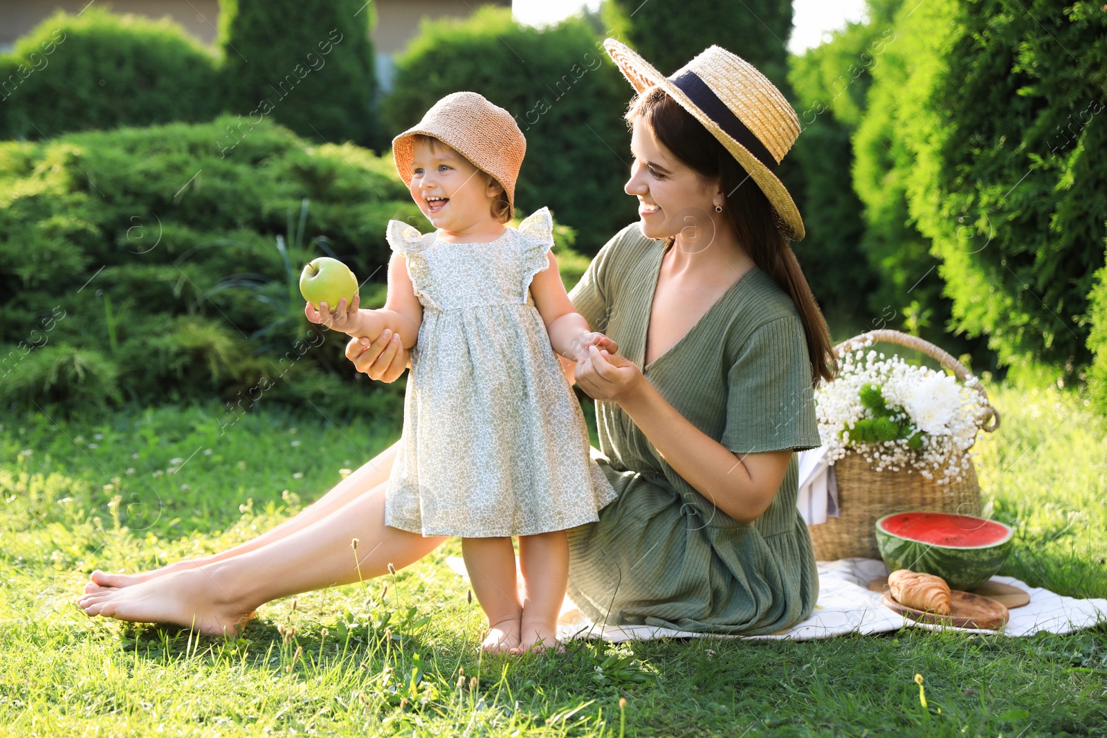 Photo of Mother with her baby daughter having picnic in garden on sunny day