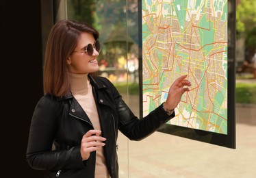Image of Young woman near public transport map at bus stop
