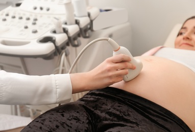 Photo of Pregnant woman undergoing ultrasound scan in clinic, closeup