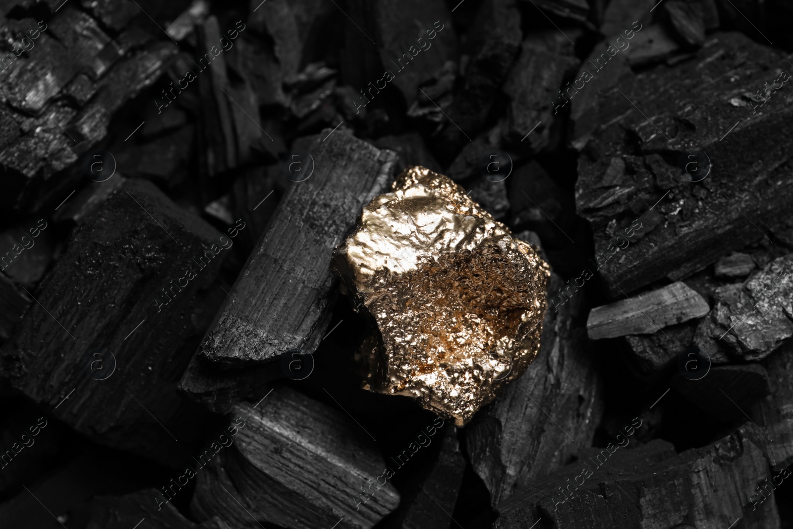 Photo of Shiny gold nugget on coals, closeup view