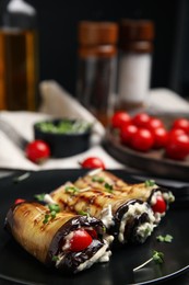 Delicious baked eggplant rolls with cheese, tomatoes and microgreens on plate, closeup