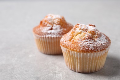 Delicious sweet muffins on light grey textured table, closeup. Space for text