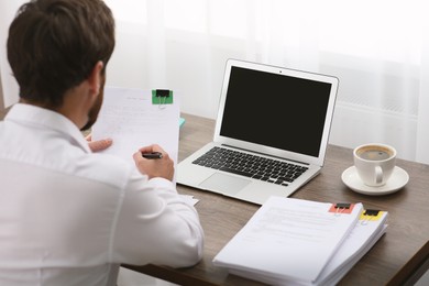 Photo of Businessman working with documents at table in office, back view