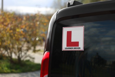 L-plate on car outdoors, closeup with space for text. Driving school