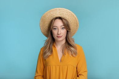 Portrait of young woman in hat on light blue background