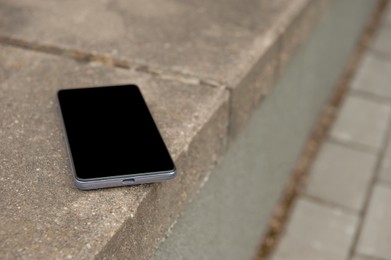 Photo of Smartphone on street curb outdoors. Lost and found