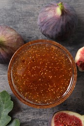 Bowl with tasty sweet jam and fresh figs on grey table, flat lay