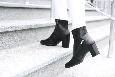Photo of Woman in stylish boots on stairs outdoors, closeup