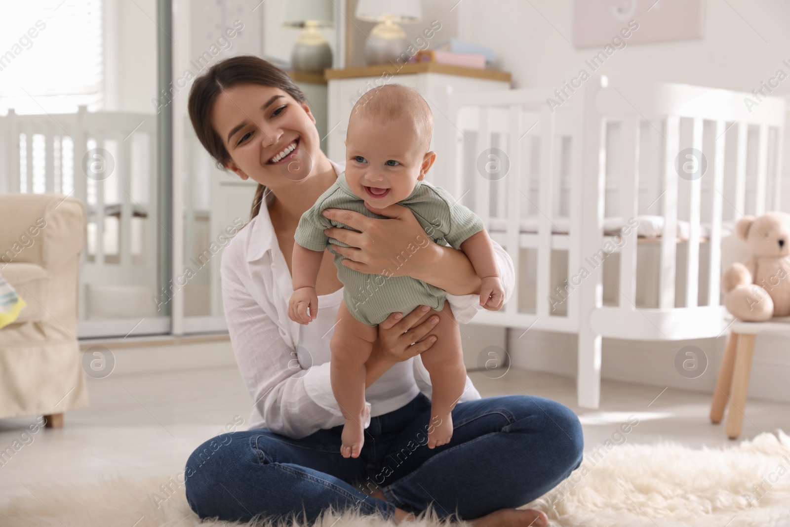 Photo of Happy young mother with her cute baby on floor at home