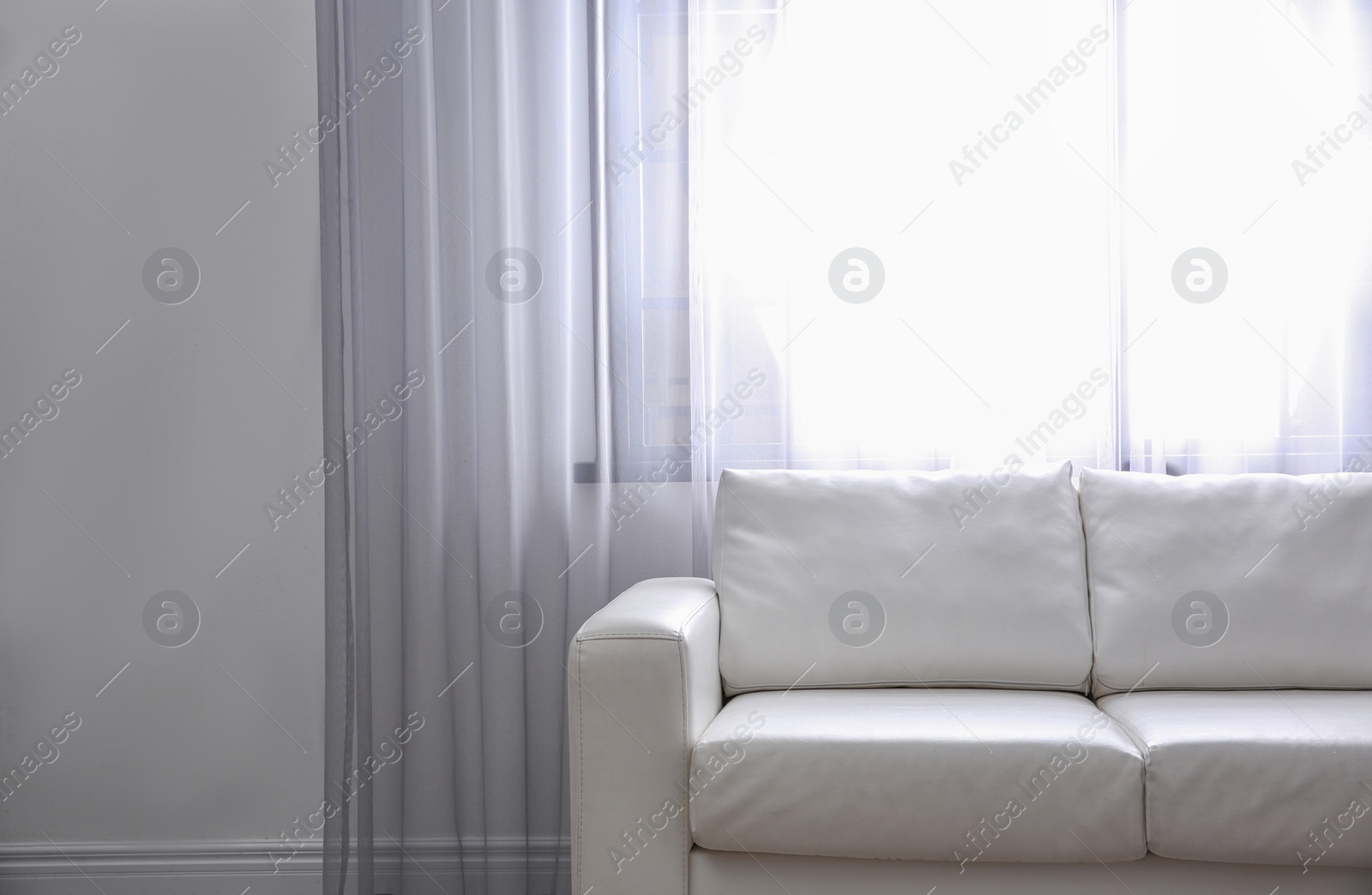 Photo of Simple living room interior with comfortable sofa near window. Space for text