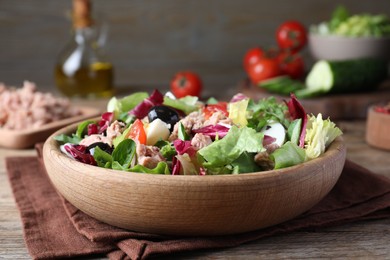 Photo of Bowl of delicious salad with canned tuna and vegetables on wooden table