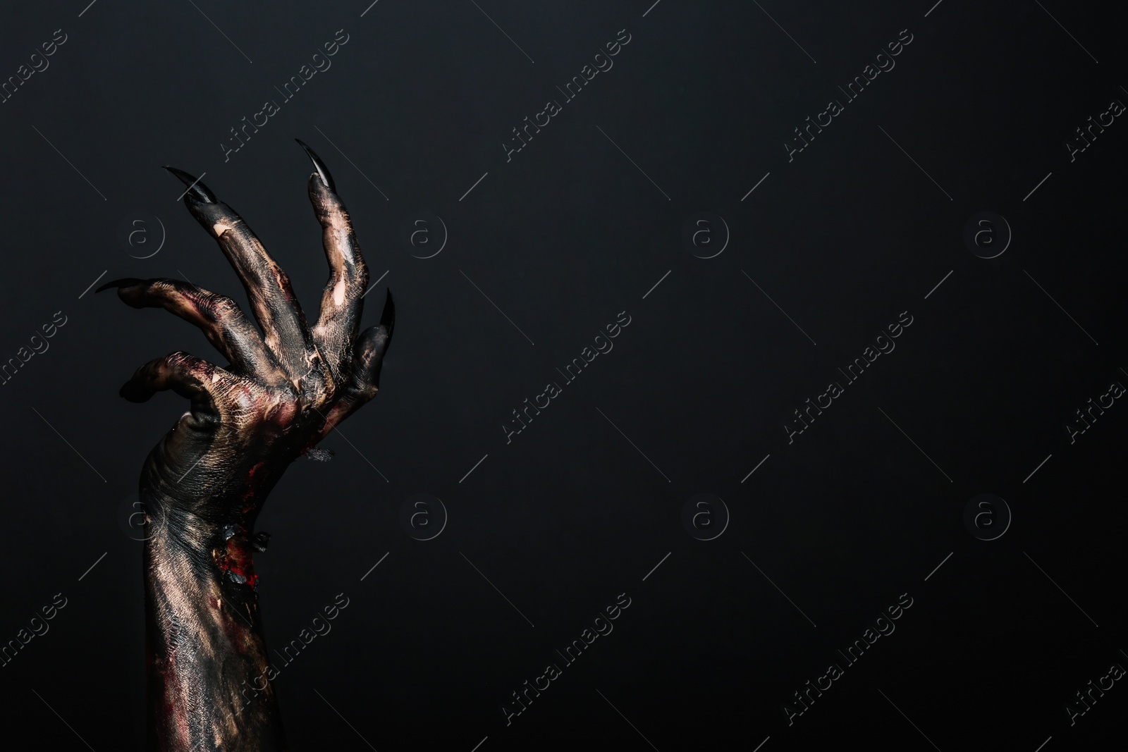 Photo of Scary monster on black background, closeup of hand with space for text. Halloween character