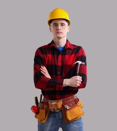 Professional repairman holding hammer on light grey background