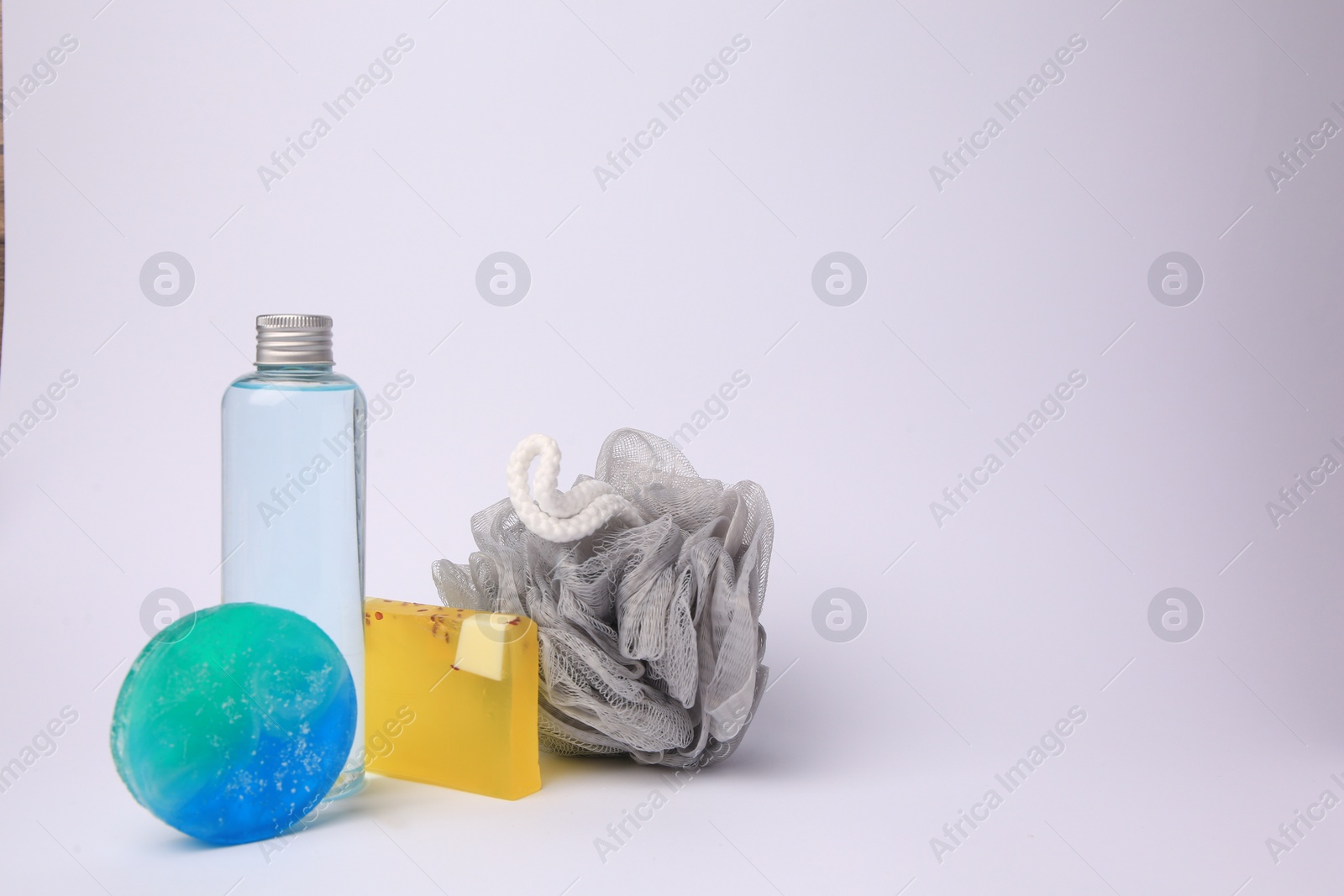 Photo of Grey shower puff and cosmetic products on white background, space for text