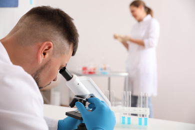 Scientist using microscope at table and colleague in laboratory. Medical research