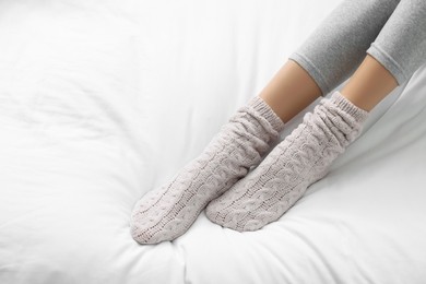 Photo of Woman wearing warm socks in comfortable bed, closeup. Space for text