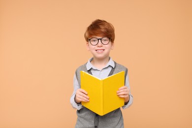 Photo of Smiling schoolboy with book on beige background