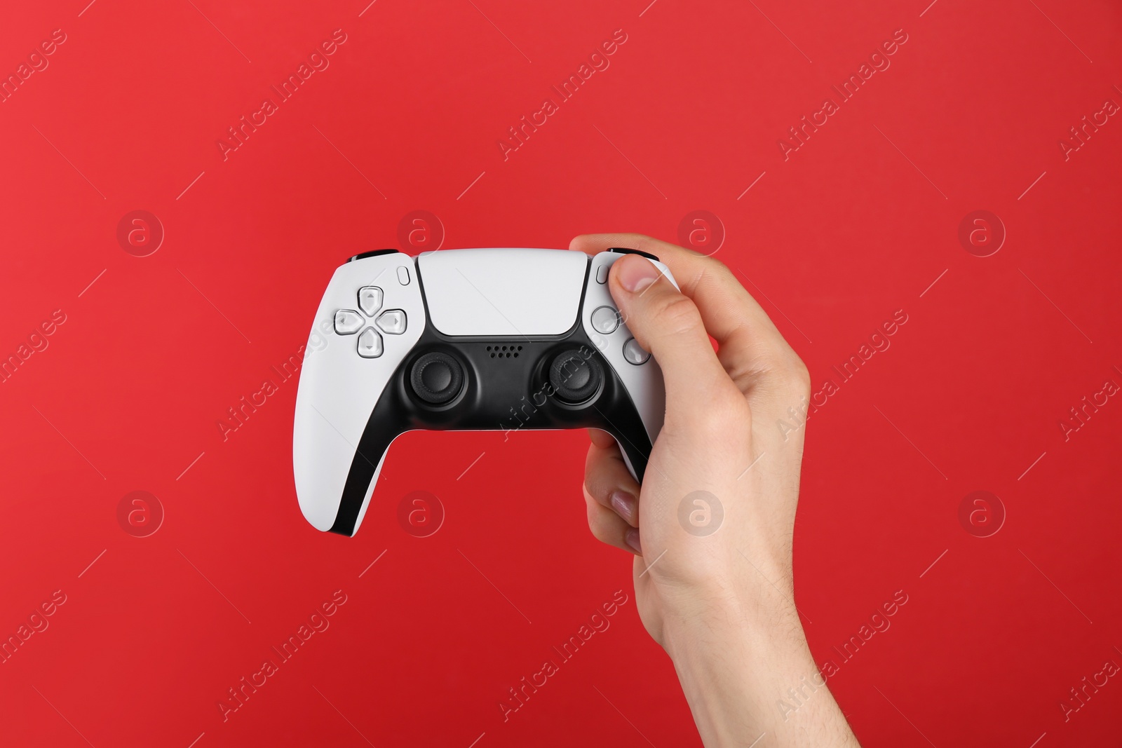 Photo of Man using wireless game controller on red background, closeup