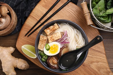 Photo of Flat lay composition with delicious vegetarian ramen and products on wooden table
