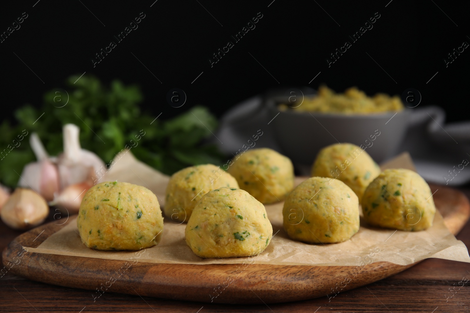 Photo of Raw falafel balls on wooden table. Space for text