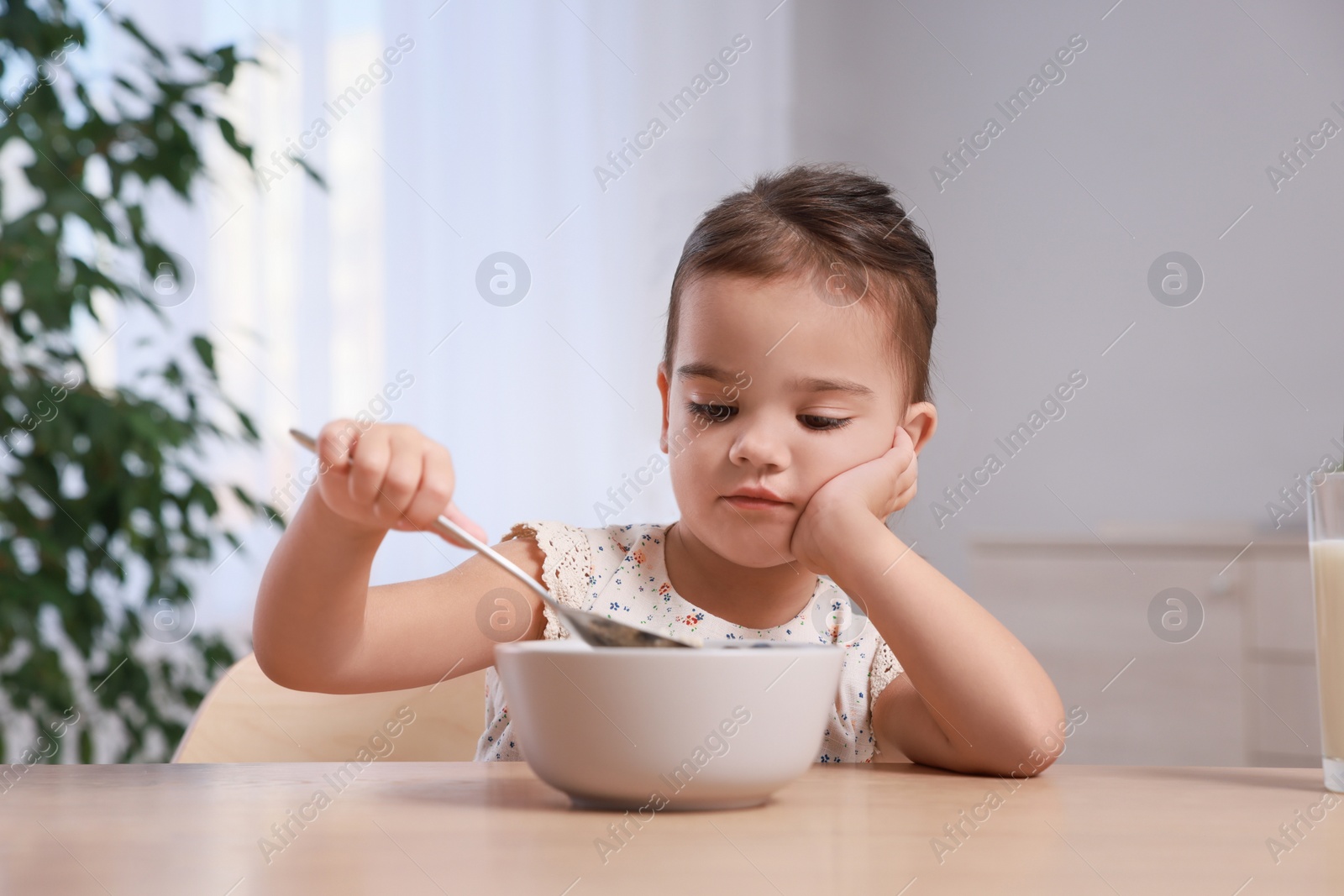 Photo of Cute little girl refusing to eat her breakfast at home