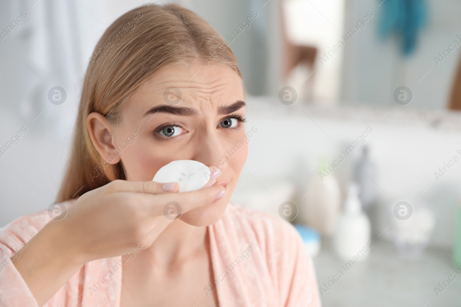 Photo of Young woman holding cotton pad with fallen eyelashes indoors