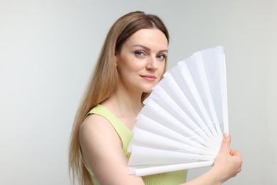 Photo of Beautiful woman with white hand fan on light grey background