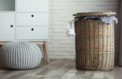 Photo of Wicker laundry basket with dirty clothes at home. Space for text