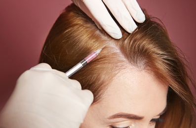 Photo of Young woman with hair loss problem receiving injection, on color background