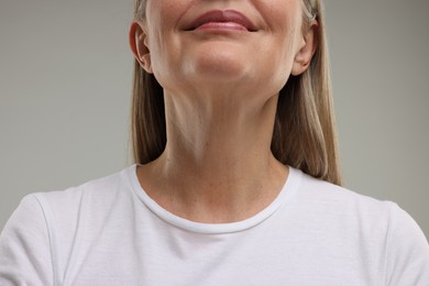 Photo of Mature woman showing her neck on grey background, closeup