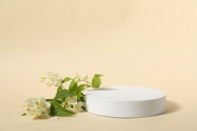 Photo of Presentation of product. White podium and beautiful jasmine flowers on beige background, space for text