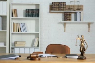 Photo of Judge's workplace with books, table, chair, mallet and figure of Lady Justice