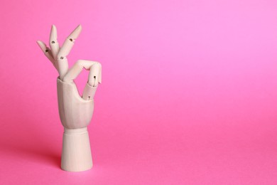 Photo of Wooden mannequin hand showing okay gesture on pink background. Space for text