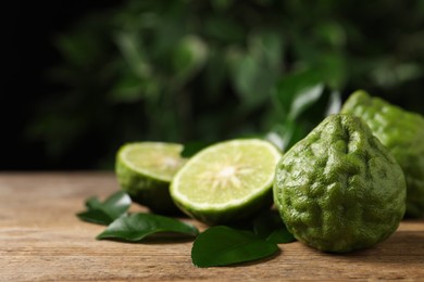 Fresh ripe bergamot fruits with green leaves on wooden table against blurred background, space for text
