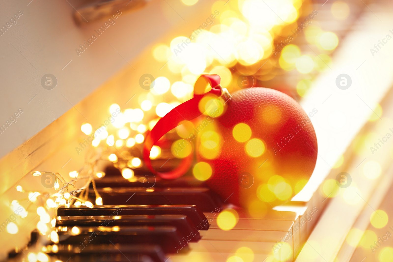 Image of Christmas and New Year music. Piano with fairy lights and festive ball, bokeh effect
