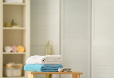 Photo of Clean towels and stones on table against blurred background