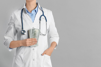 Doctor with bribe on grey background, closeup. Corruption in medicine